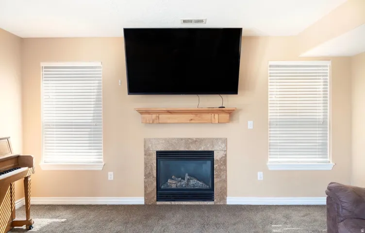 Central fireplace featuring a stone surround and a natural wood mantel