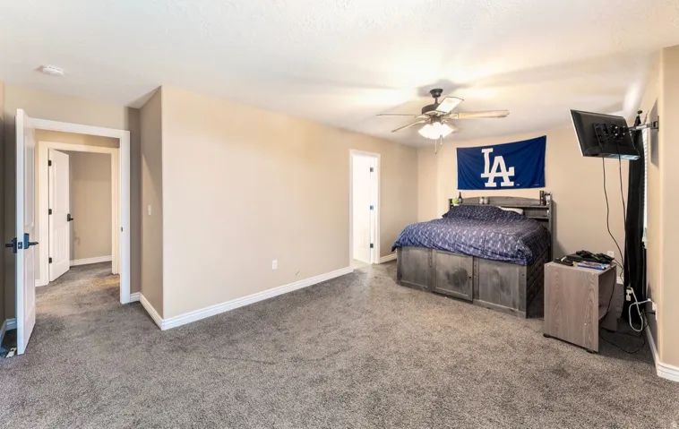 Carpeted room featuring neutral wall paint, white trim, a ceiling fan with integrated lighting, and multiple doorways