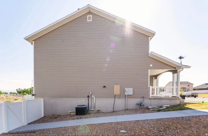Side elevation featuring horizontal siding, a covered porch with white railings, and a concrete foundation