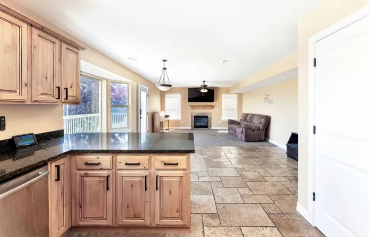 Open-concept living space featuring wood cabinetry, dark countertops, and stainless steel appliances