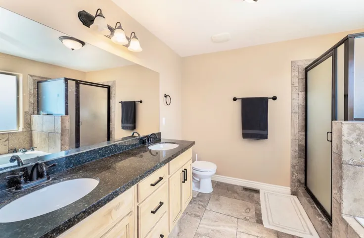 Double vanity with dark granite-finish countertop and undermount sinks