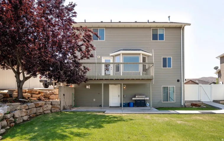 Rear exterior featuring gray siding, a two-story design, and a raised wooden deck with a bay window