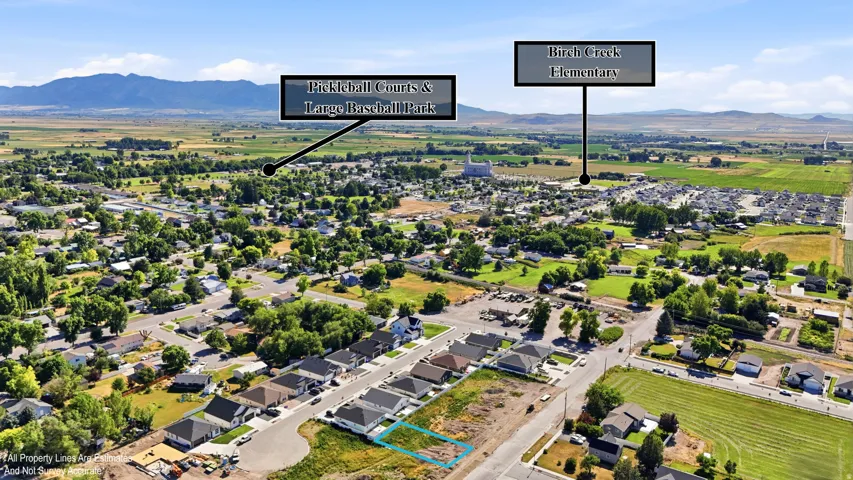 Aerial overview of a residential development with surrounding green spaces and distant mountains