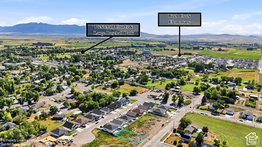 Aerial overview of a residential development with surrounding green spaces and distant mountains