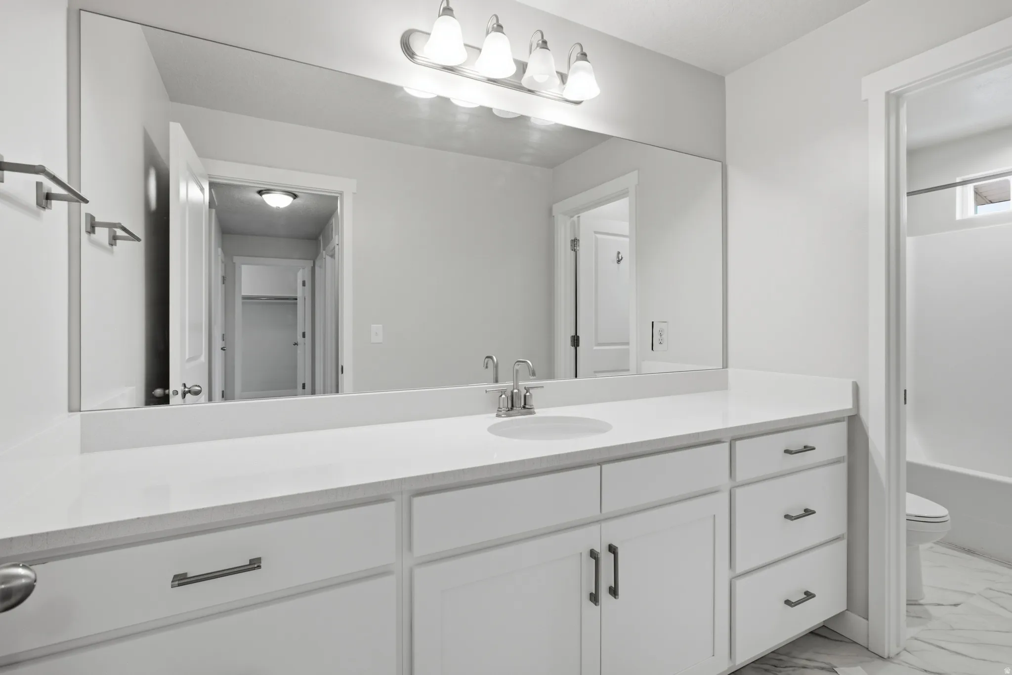 Spacious bathroom vanity featuring a white countertop, undermount sink, and brushed nickel faucet