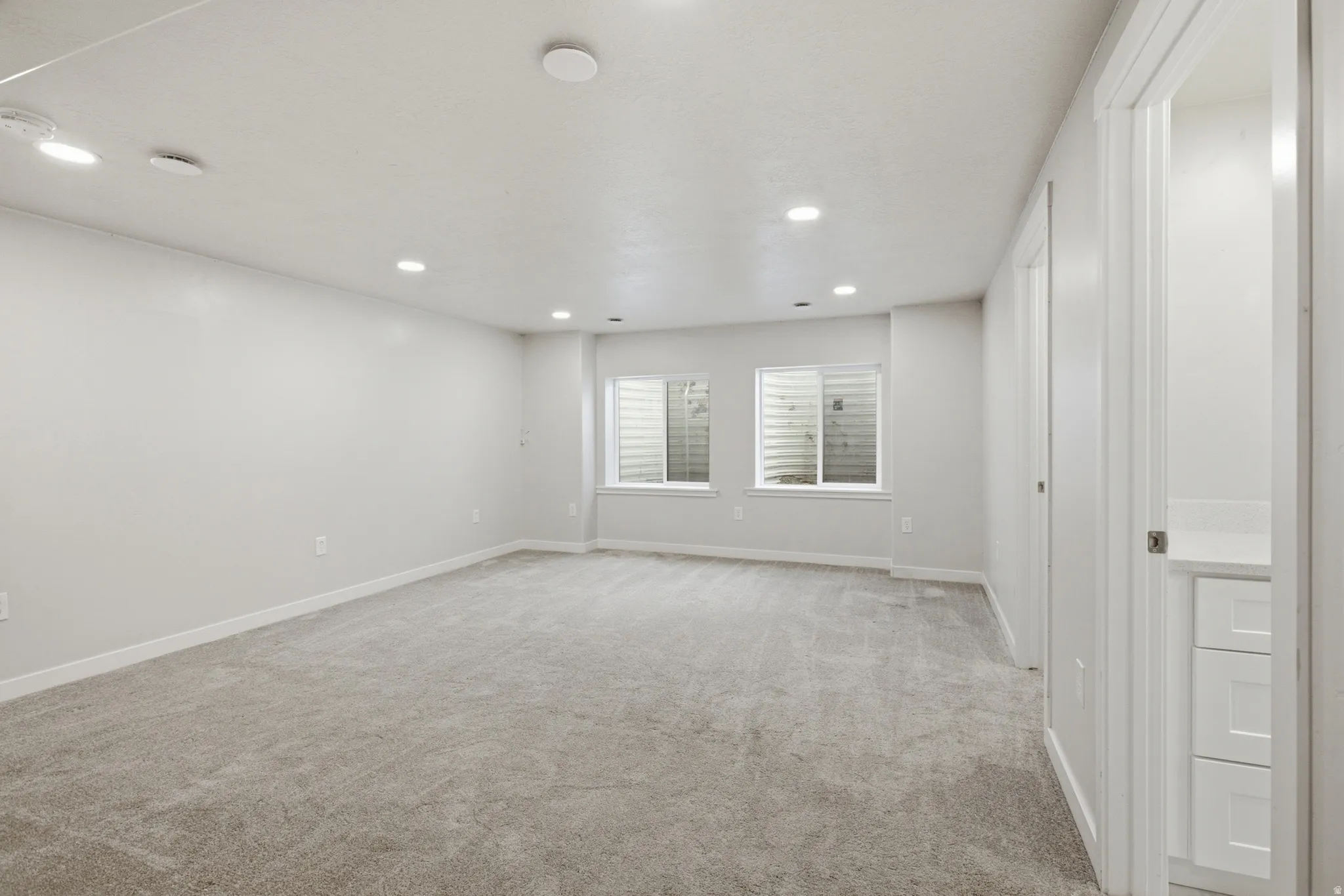 Spacious room featuring neutral carpeting and recessed lighting