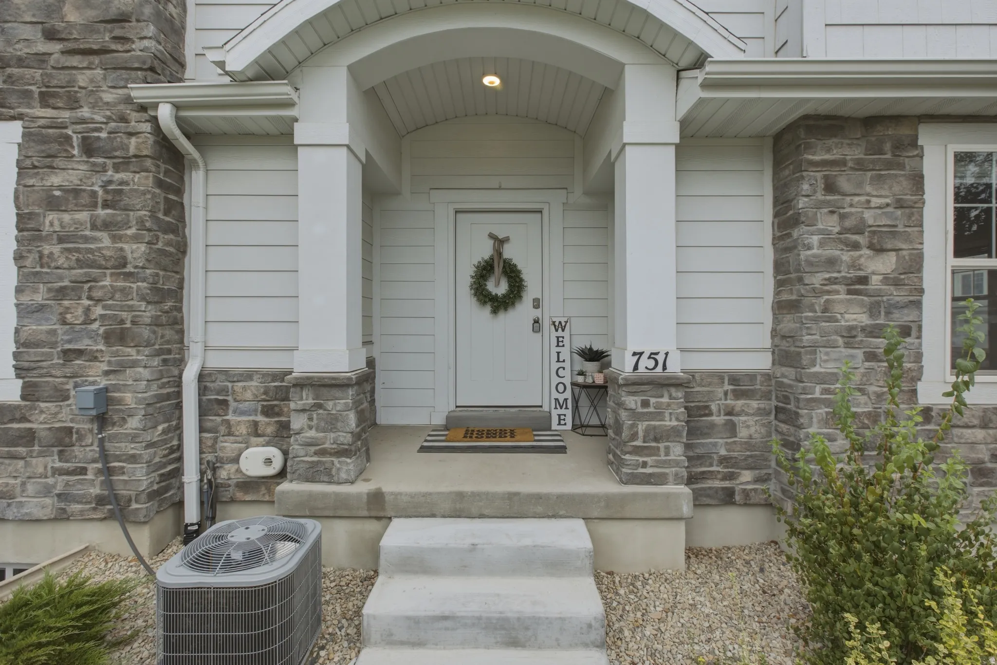 Entryway featuring a white door, stone veneer facade, and concrete steps