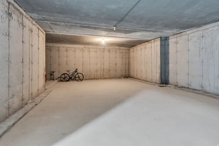 Spacious concrete basement featuring a poured concrete floor and exposed concrete walls