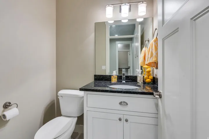 Bathroom vanity featuring a dark speckled countertop, white cabinetry with silver hardware, and an undermount sink