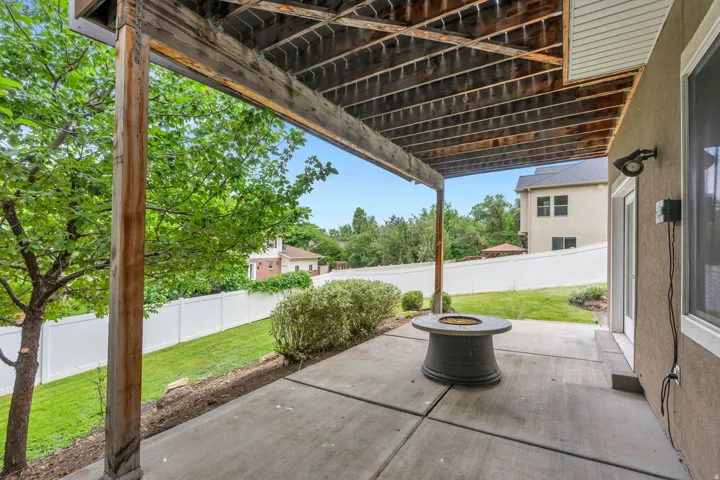 Covered concrete patio with an integrated fire pit, providing a functional outdoor area
