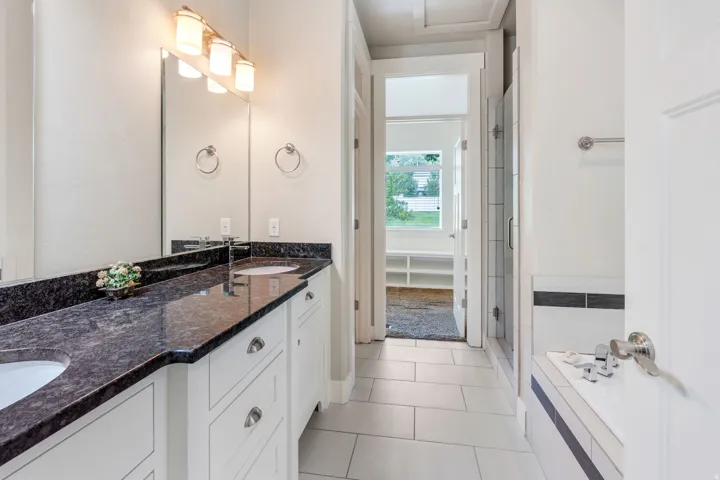 Spacious bathroom featuring a double vanity with dark countertops and undermount sinks, a large mirror, and a contemporary three-light fixture