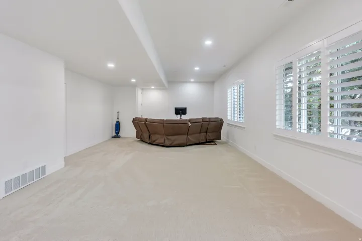 Spacious room featuring light-toned carpeting, white walls, and recessed lighting