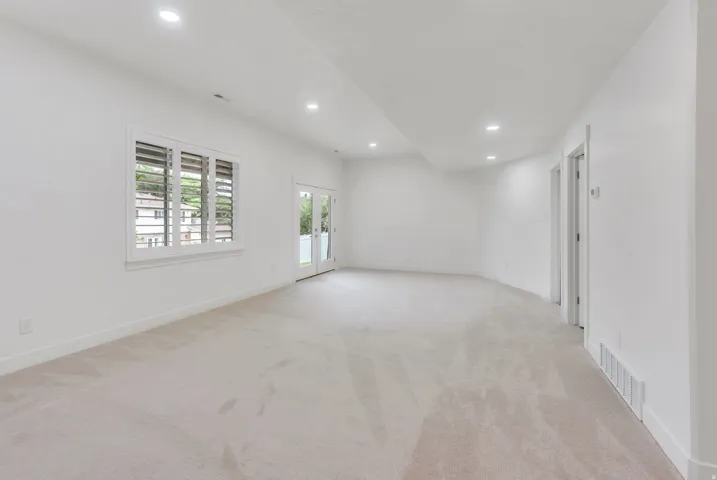 Spacious room featuring light-toned carpeting, recessed lighting, and white walls