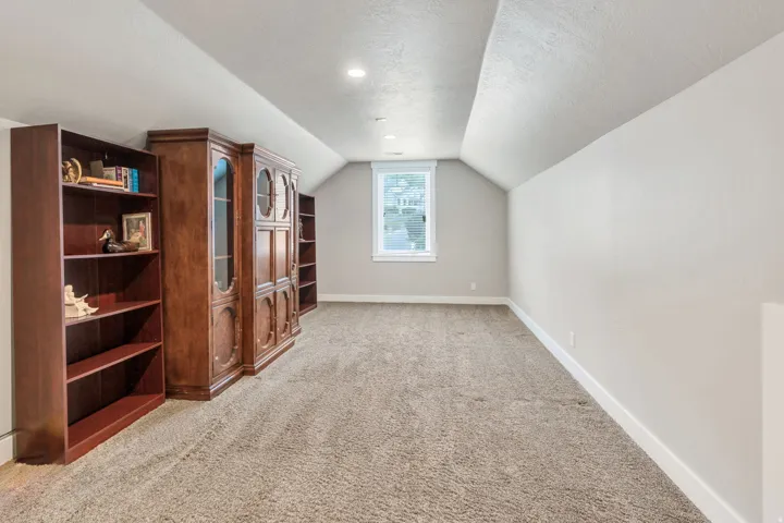 Carpeted bonus room featuring a window, recessed lighting, and sloped ceilings