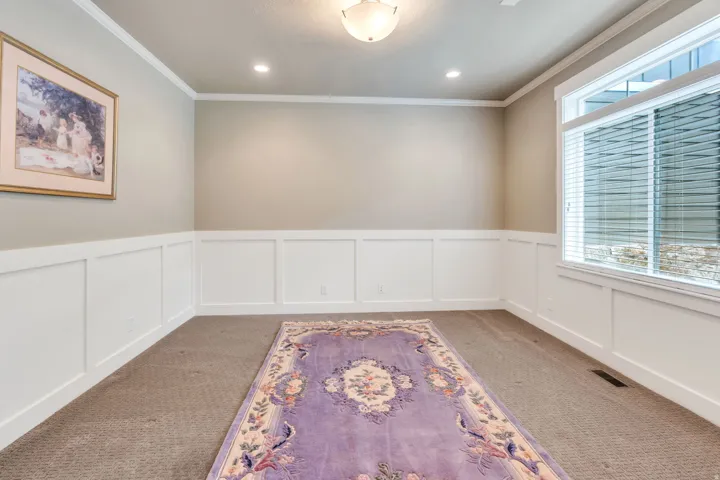 Room featuring wainscoting, crown molding, a large window, recessed lighting, and a flush mount ceiling fixture