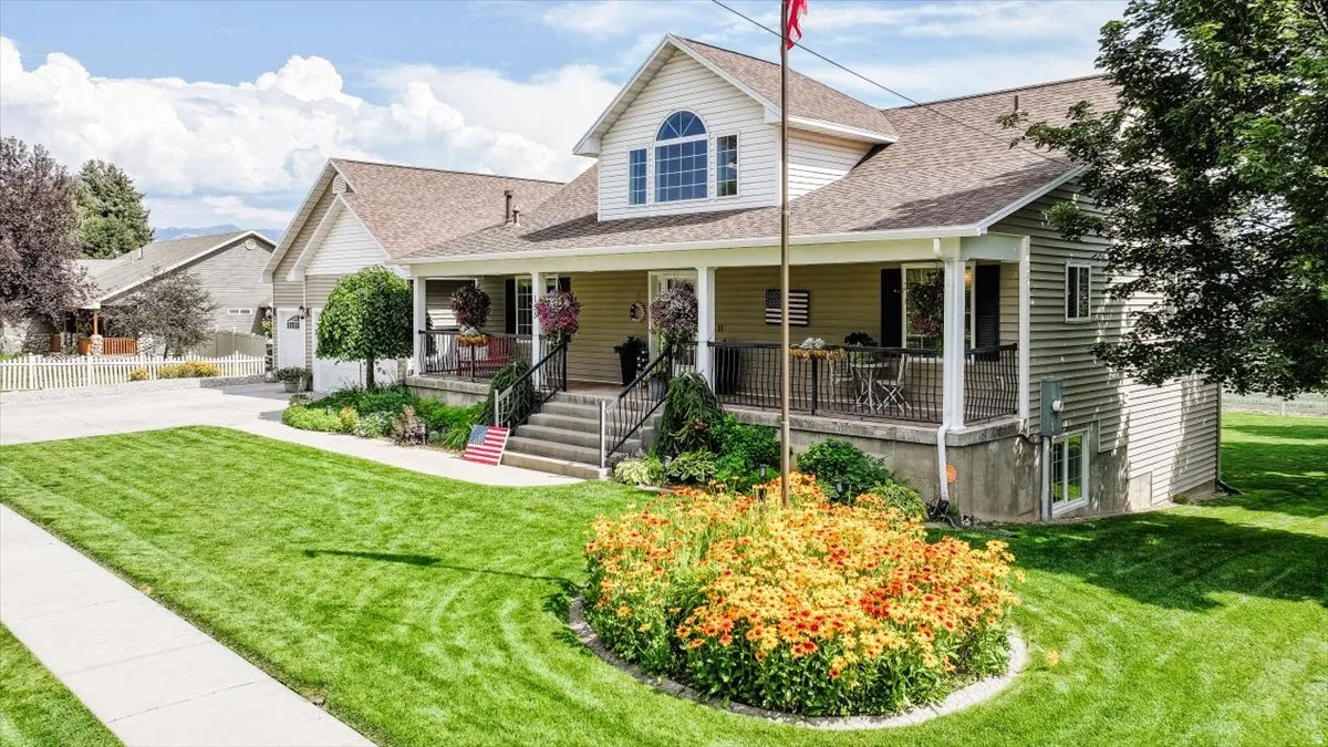 Two-story home featuring a full-width covered porch with black railings, a prominent arched window, and light-colored siding