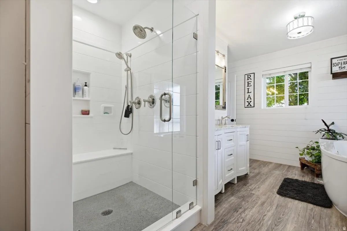 Spacious shower enclosure with glass doors, built-in bench, and dual shower heads