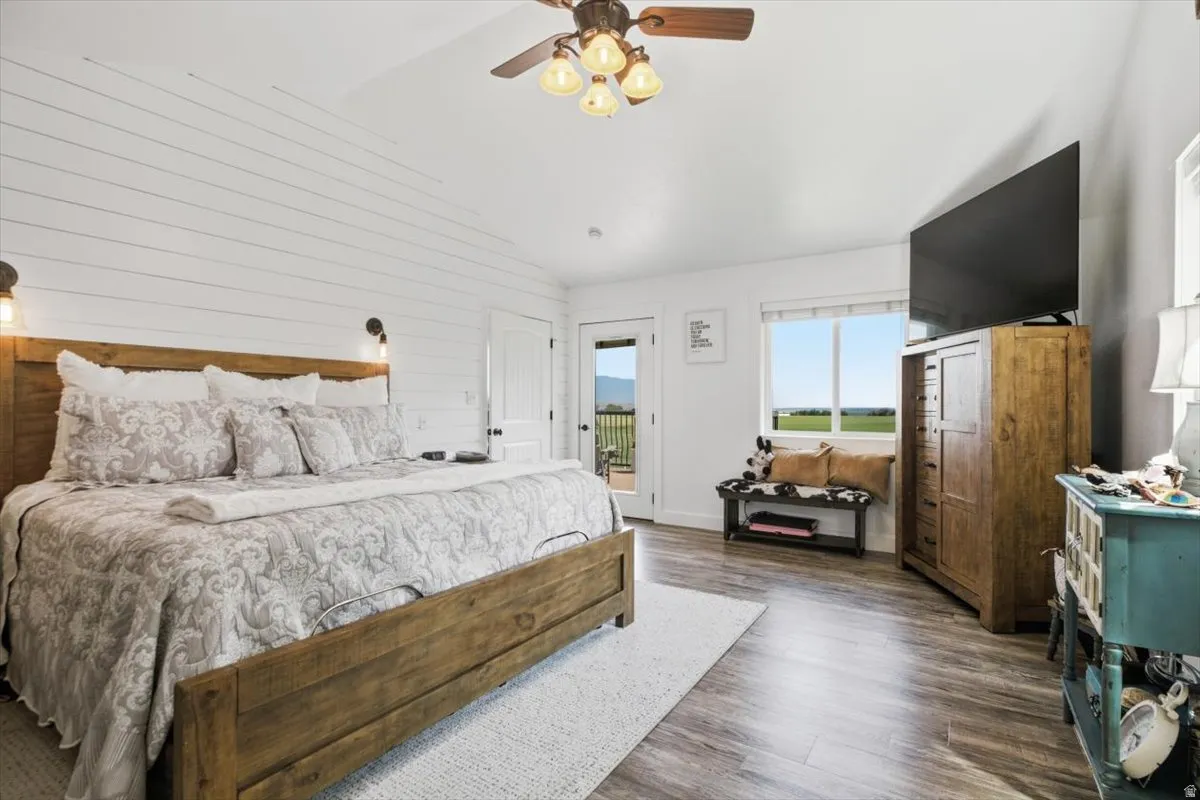 Shiplap accent wall, wood-finish flooring, and a ceiling fan with integrated lighting
