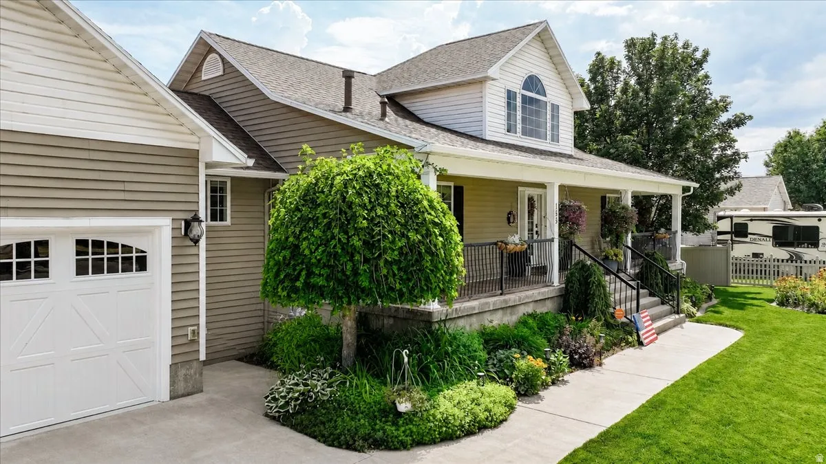 Exterior featuring a covered front porch with white columns, a dormer window, and a white garage door with decorative windows