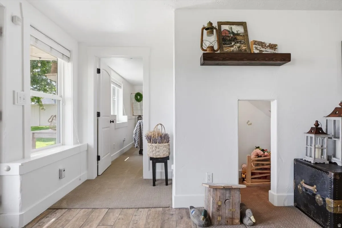 Hallway featuring wood-finish flooring, white trim, and a recessed wall opening
