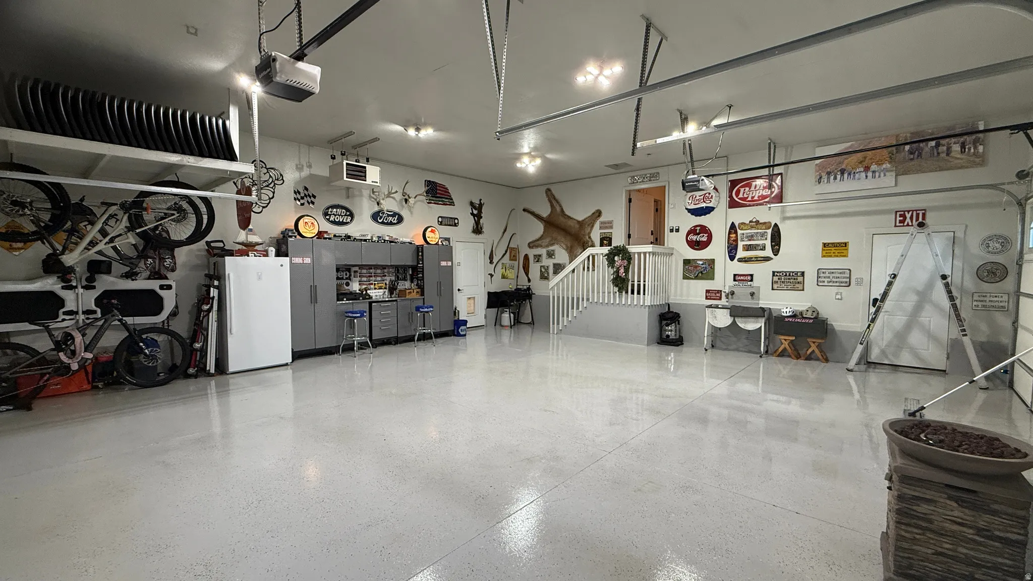 Spacious garage featuring a durable epoxy floor finish, extensive built-in cabinetry, and a dedicated storage rack system