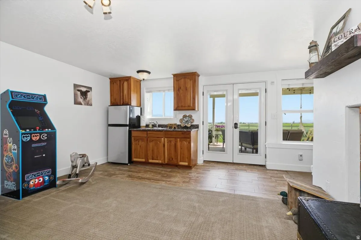 Lounge area featuring a built-in wet bar with wood cabinetry, stainless steel refrigerator, and dark countertops
