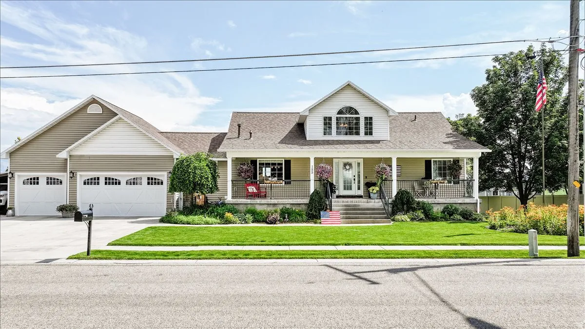 Siding exterior with a covered porch, dormer window, and a three-car garage