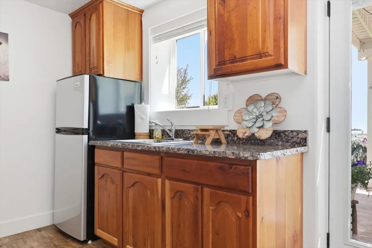 Compact kitchen area featuring wood cabinetry, a mottled countertop, and an undermount sink