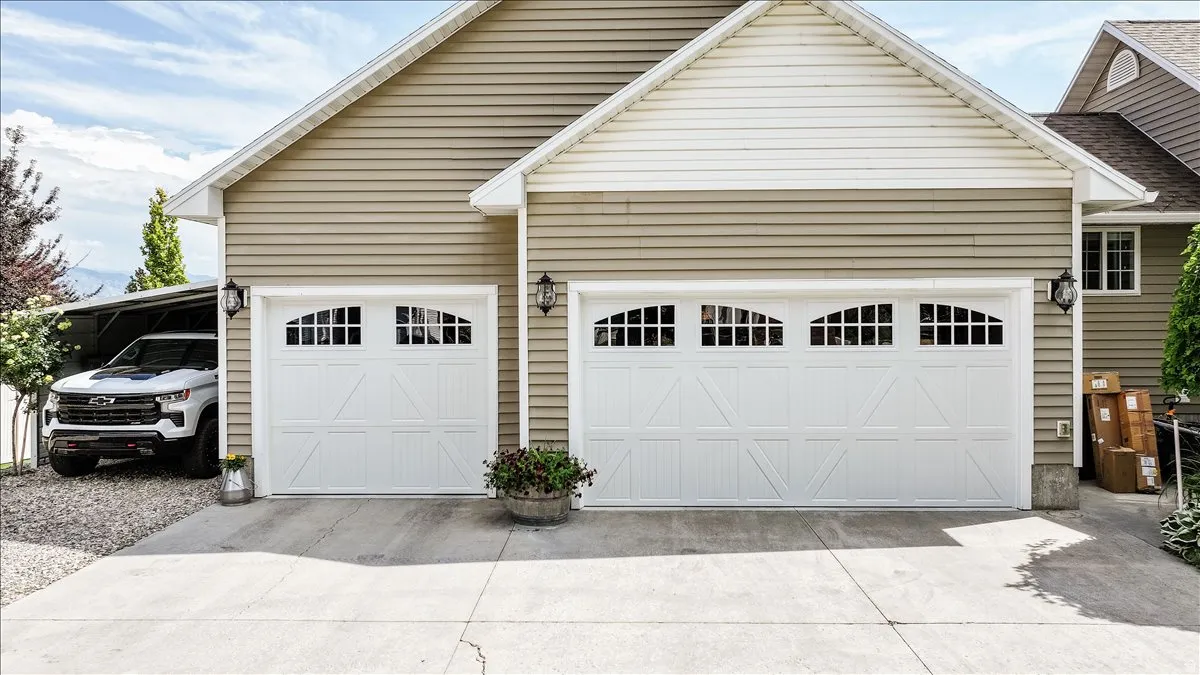 Two white garage doors with arched window panels and decorative hardware