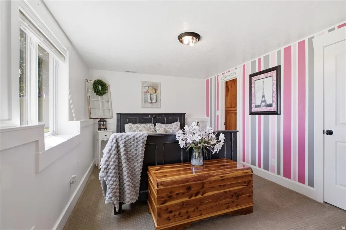 Bright room featuring a window with white trim, board and batten wall detailing, a striped accent wall, and neutral carpeting