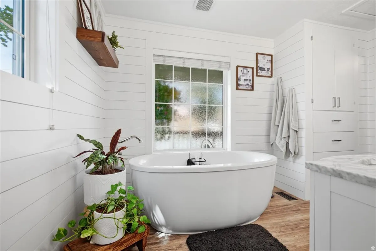Freestanding soaking tub with a floor-mounted faucet, set against white shiplap walls