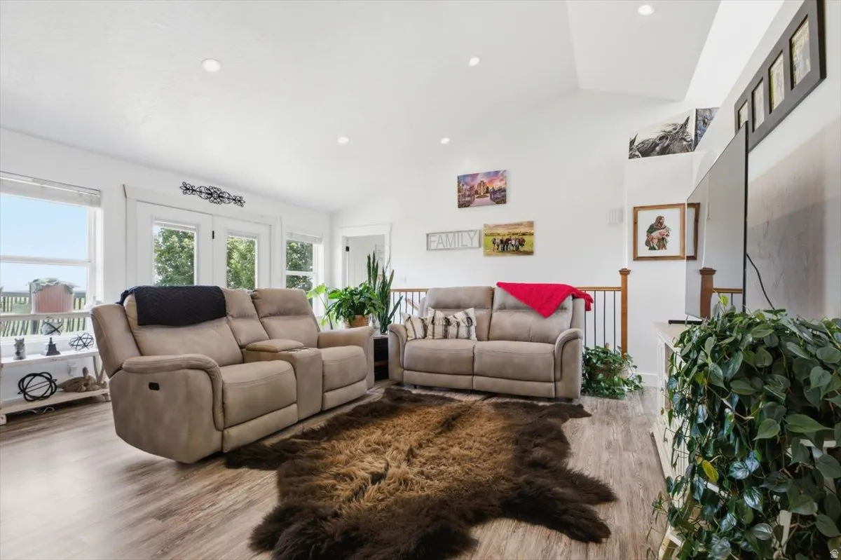Vaulted ceilings illuminate this living space, featuring recessed lighting, light wood-finish flooring, and white painted walls