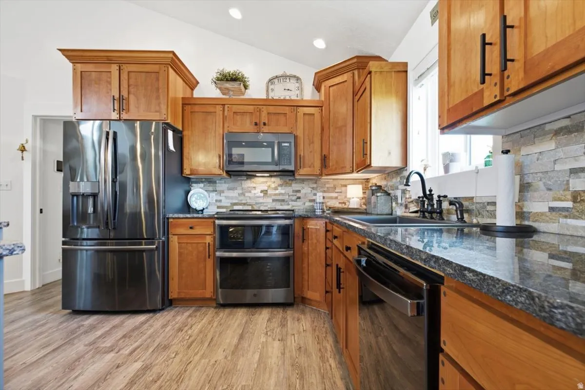 Kitchen featuring wood-finish flooring, natural wood cabinetry, and a stacked stone backsplash
