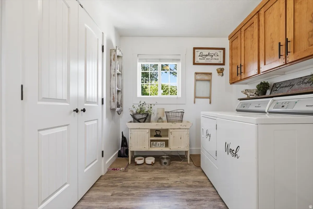 Utility room featuring wood-finish flooring, white paneled doors, a window with natural light, and upper wood cabinetry with dark hardware