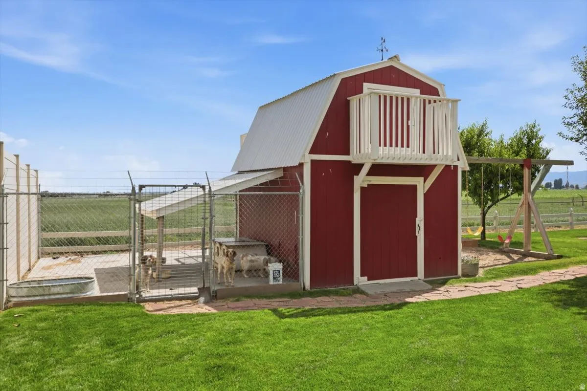 Red barn-style outbuilding featuring a white metal roof, upper-level balcony with white railings, and a lower-level entrance