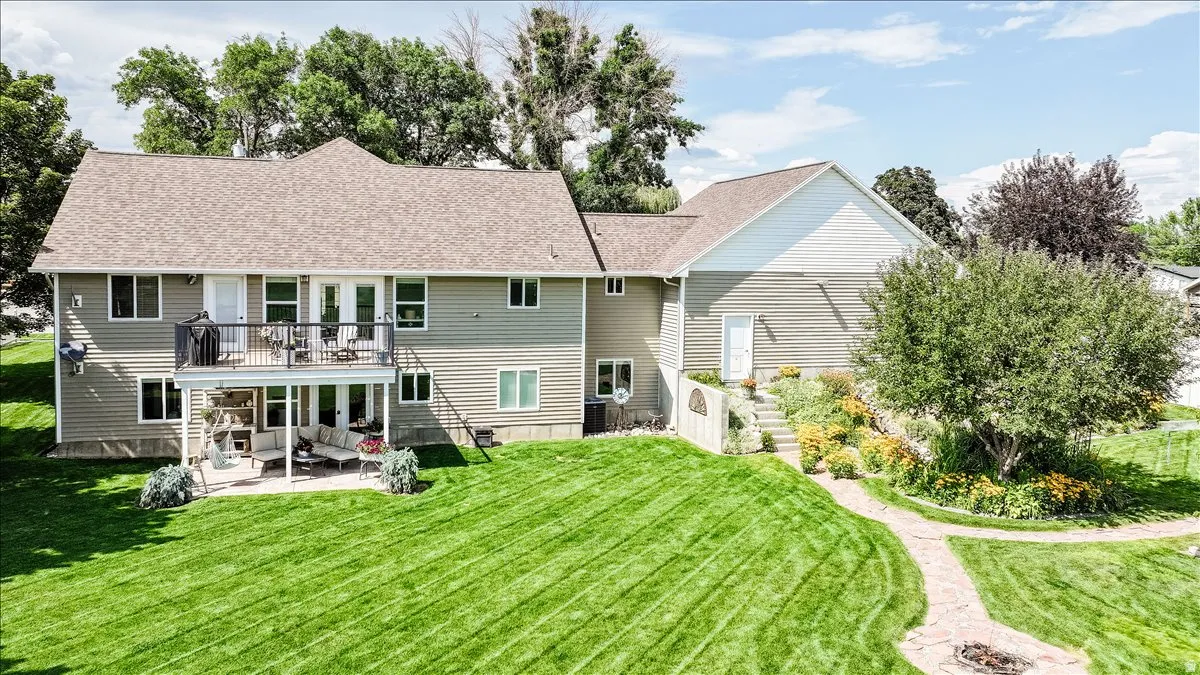 Spacious property featuring an expansive lawn, multi-level patio and deck, and established landscaping