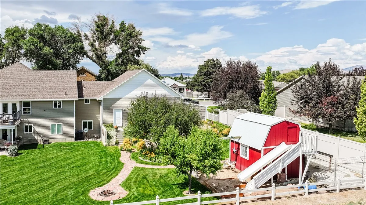 Expansive backyard with a manicured lawn, paved walkway, and a fire pit area
