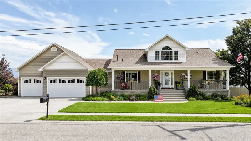 Charming exterior featuring a covered front porch, dormer window, and an attached three-car garage