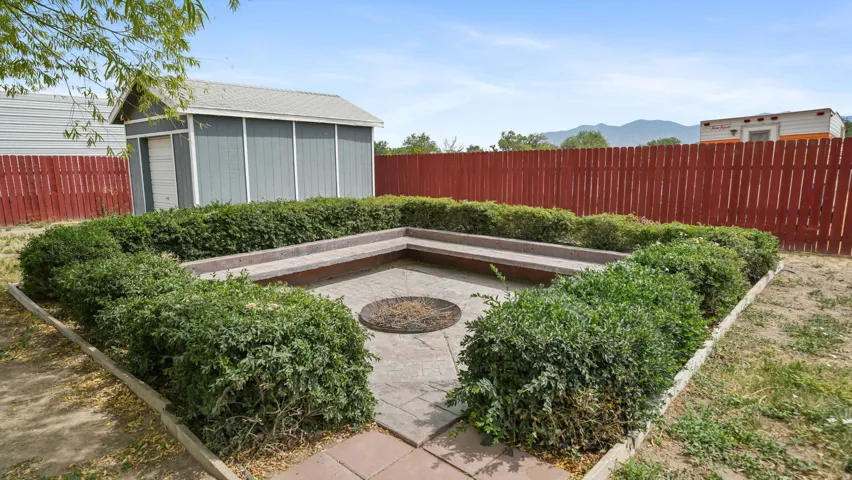 Patio area featuring integrated seating, a central fire pit, and surrounding manicured hedges