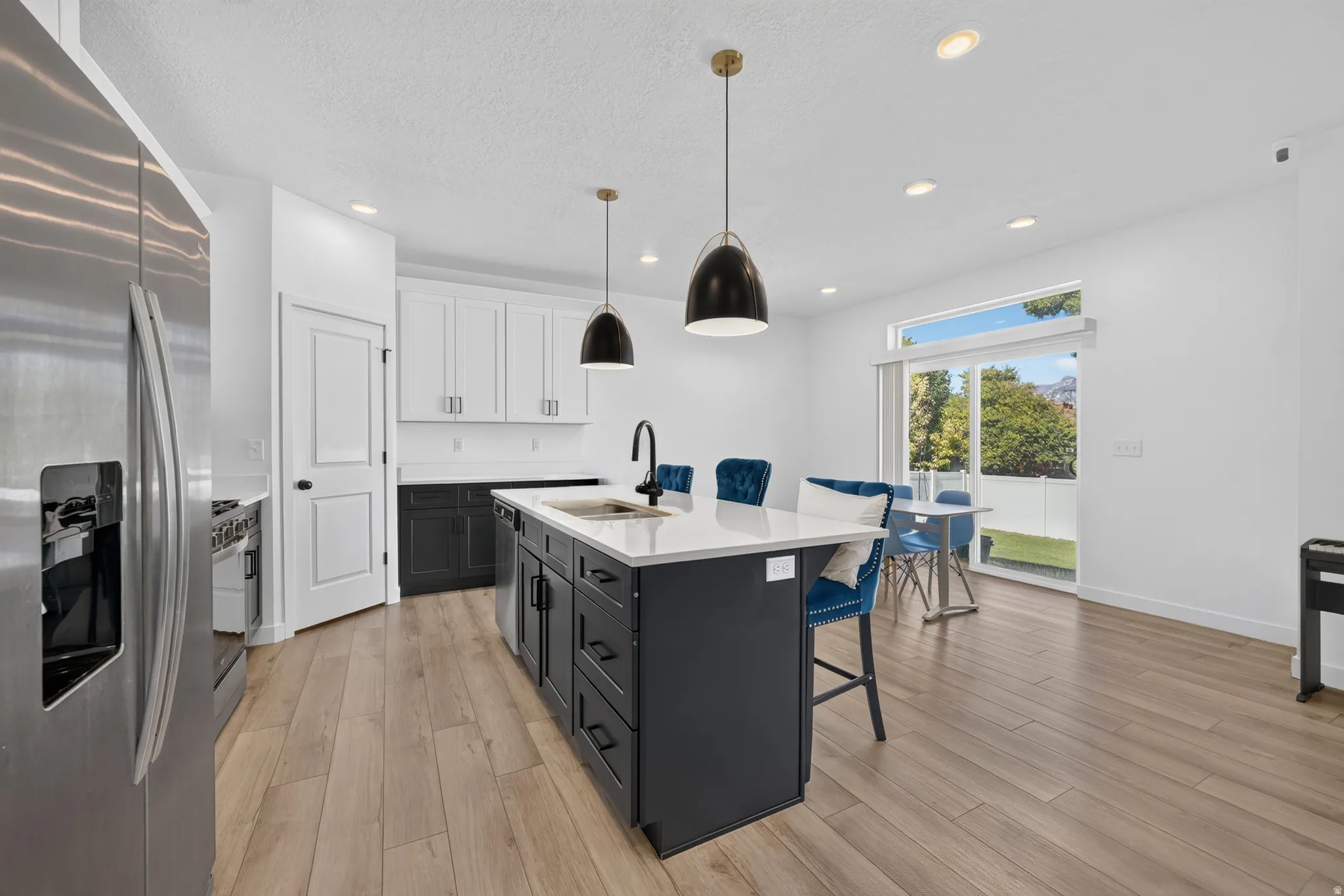 Modern kitchen featuring a large central island with seating, stainless steel appliances, and wood-finish flooring