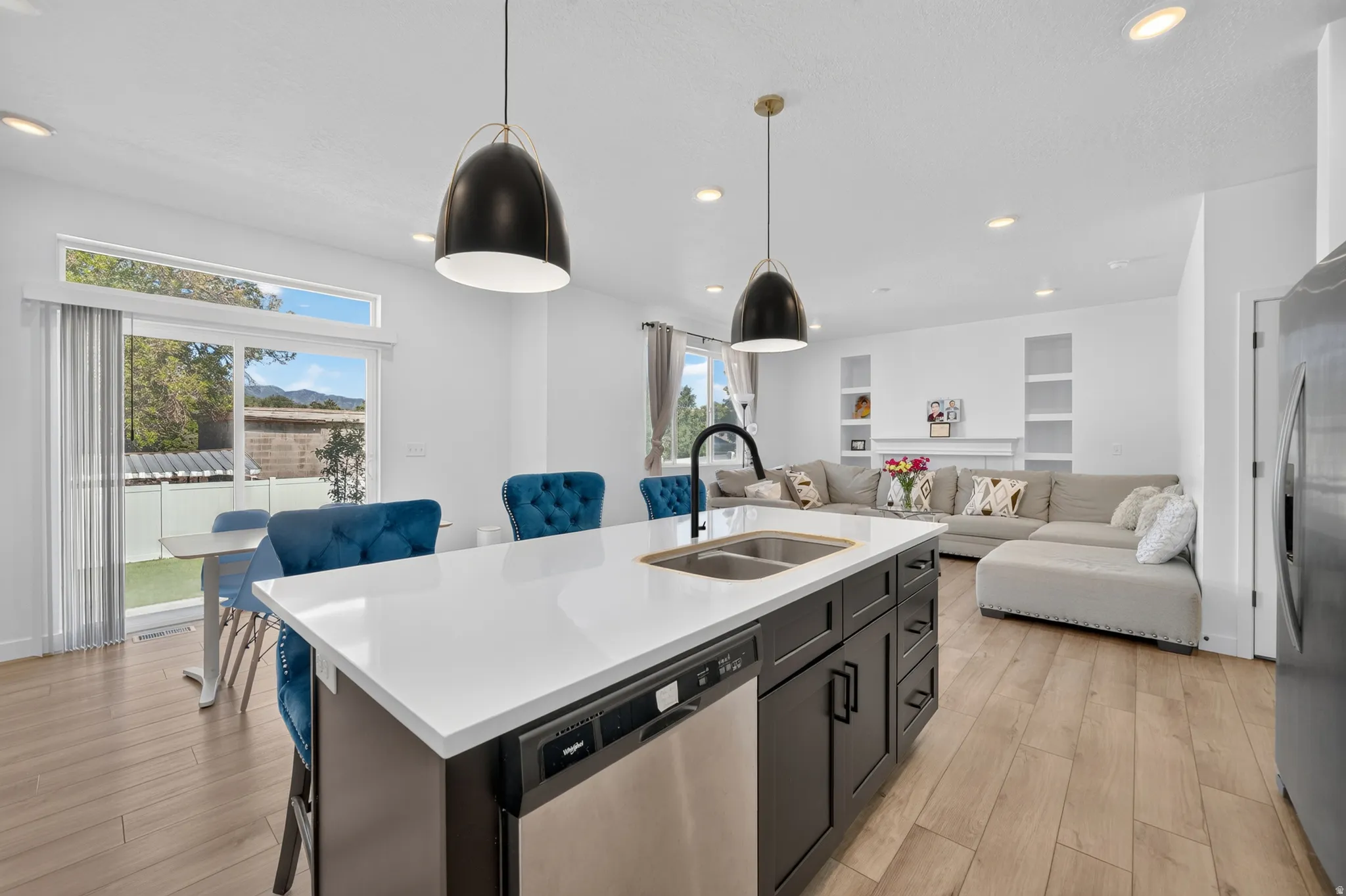 Kitchen island featuring a white countertop, dual basin sink with a black gooseneck faucet, and dark cabinetry