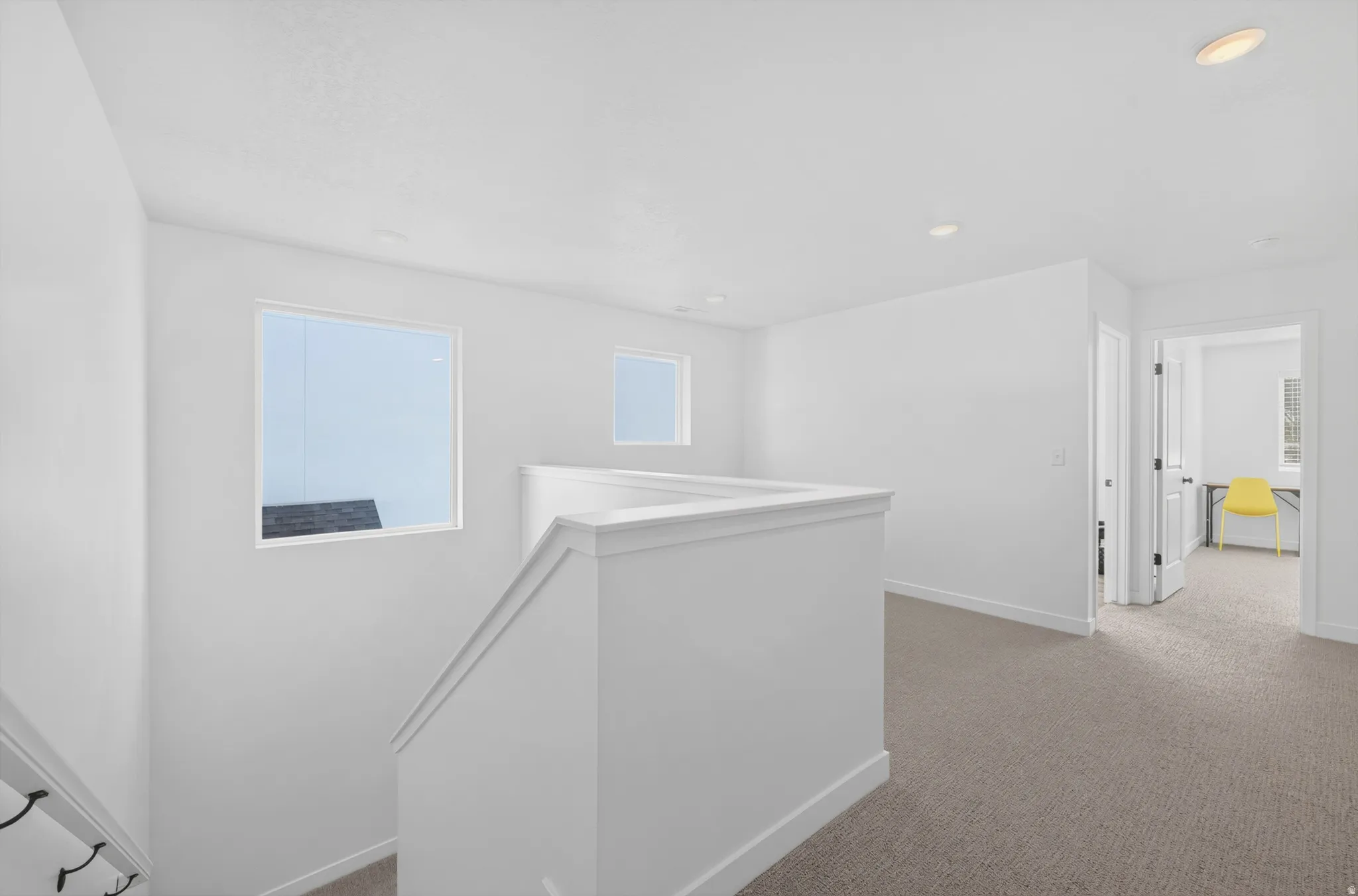 Staircase featuring white balustrade and dark stair railing, complemented by two rectangular windows and recessed lighting