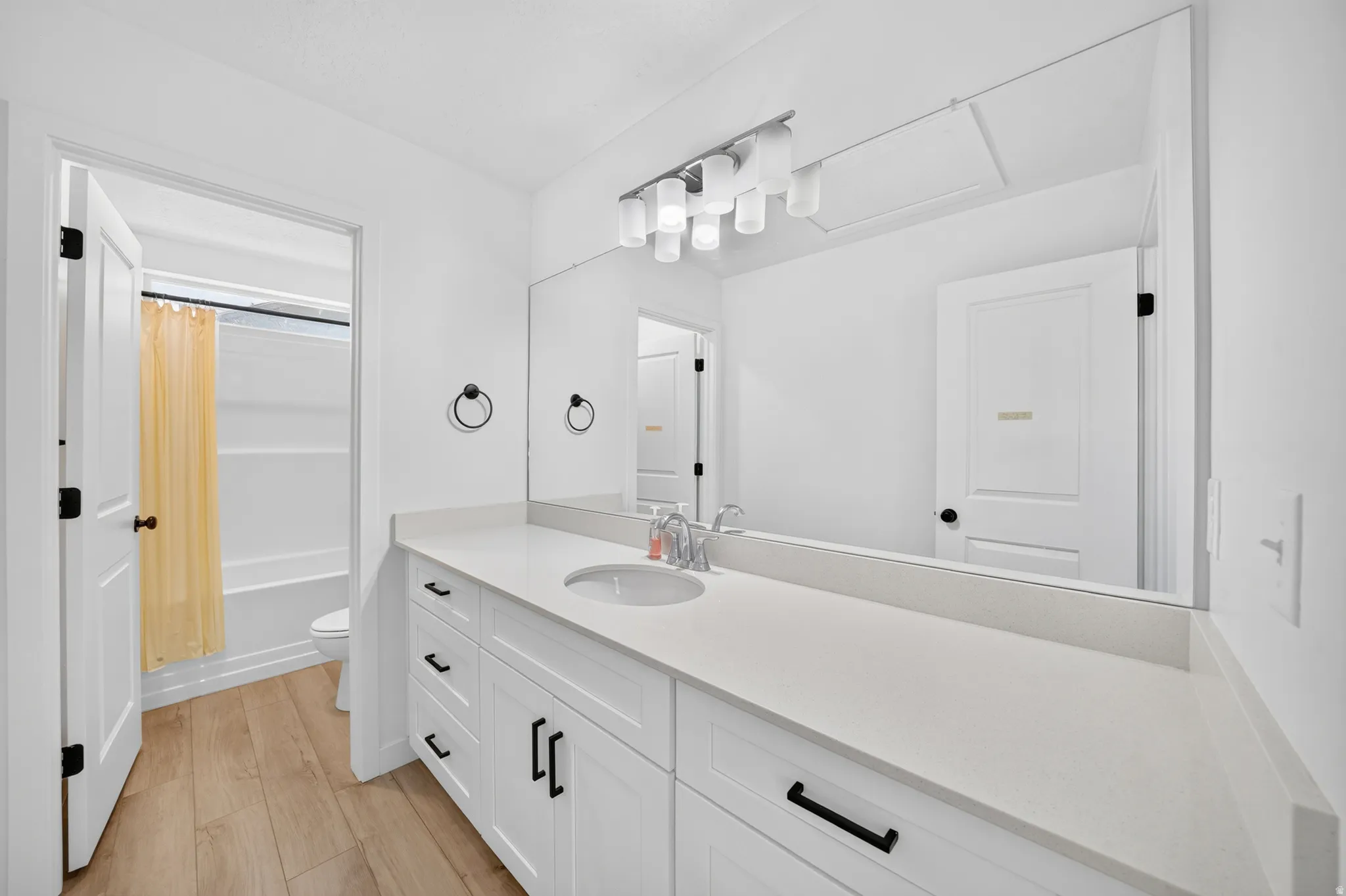 Expansive vanity featuring white cabinetry with black hardware, a light-toned countertop, and an integrated sink