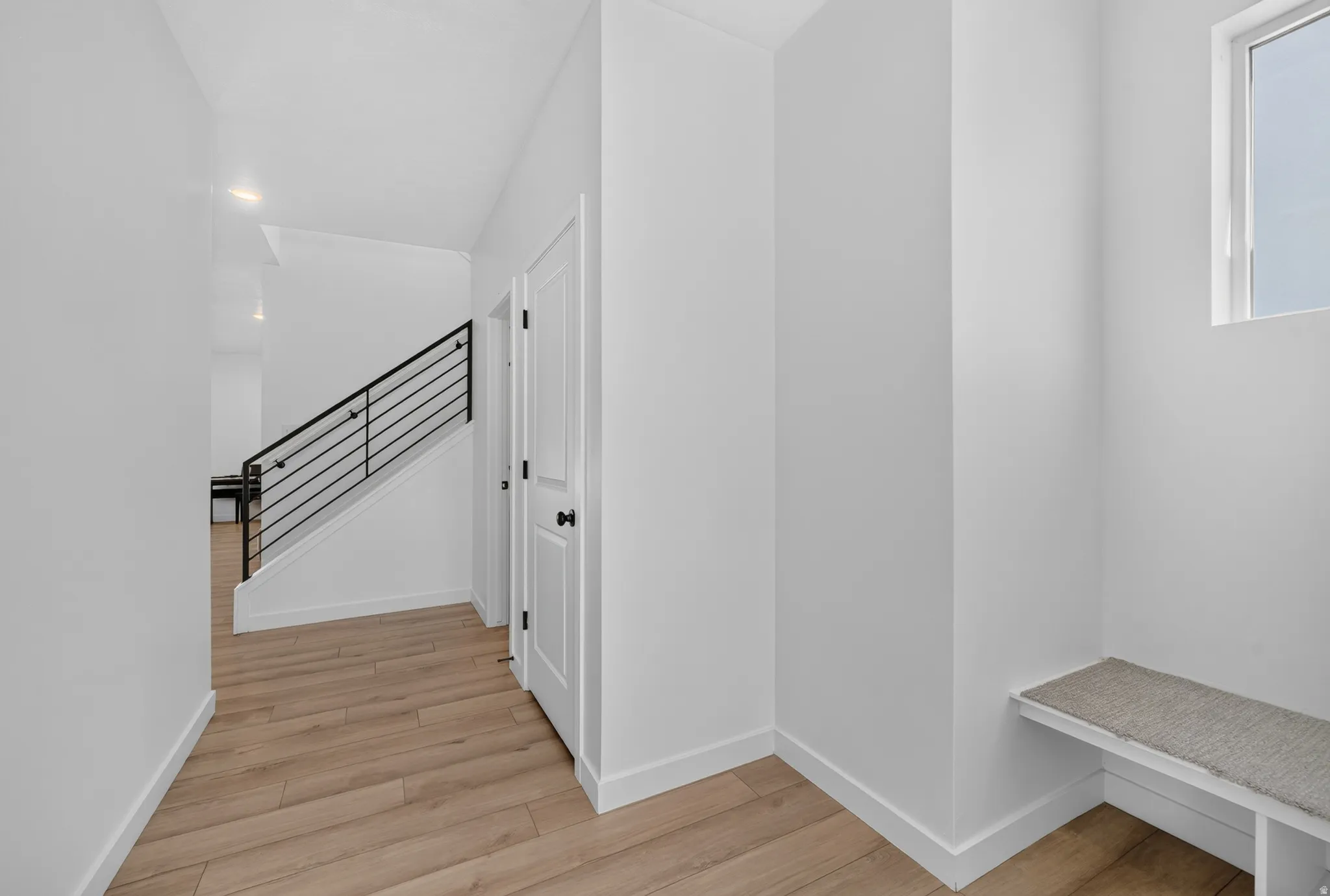 Foyer featuring wood-finish flooring, white walls, and a built-in bench below a window