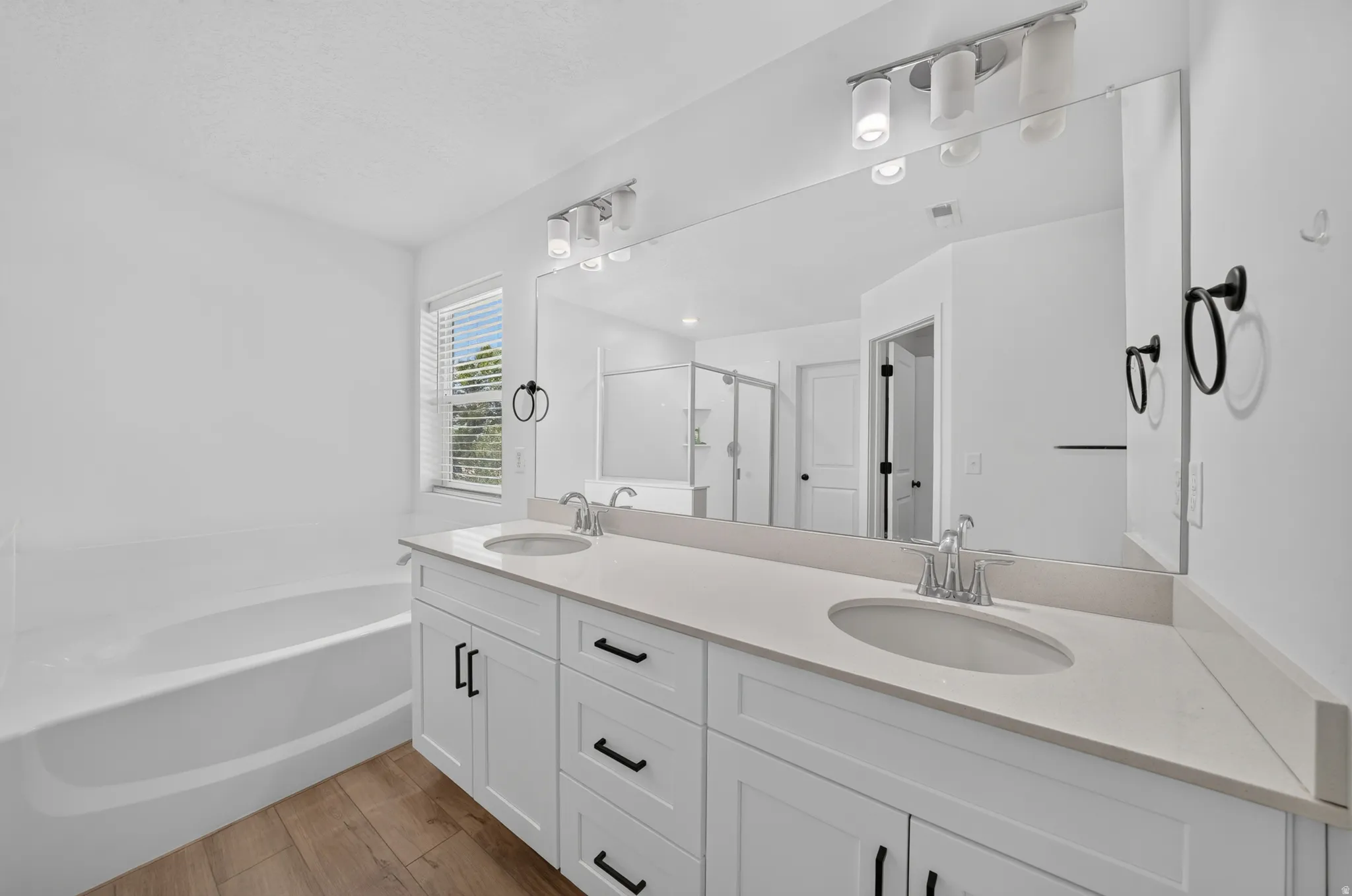 Double vanity featuring white cabinetry with black hardware, undermount sinks, and a light-toned countertop