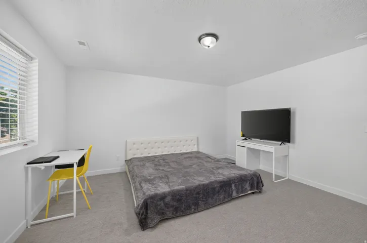 Carpeted room with a window featuring horizontal blinds