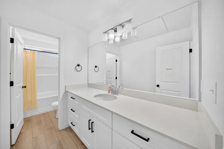Expansive vanity featuring white cabinetry with black hardware, a light-toned countertop, and an integrated sink