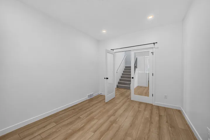 Room featuring wood-finish flooring, white baseboards, and neutral wall paint