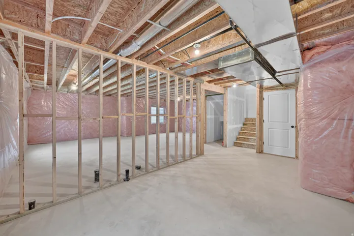 Unfinished basement space featuring exposed wood framing and insulation