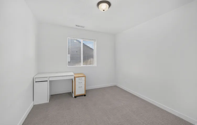 Neutral-toned wall-to-wall carpeting complements the white walls